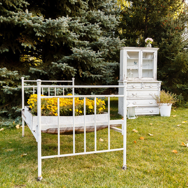 Ліжко з жовтими квітами і стара біла шафа на фоні
  - Фото, зображення