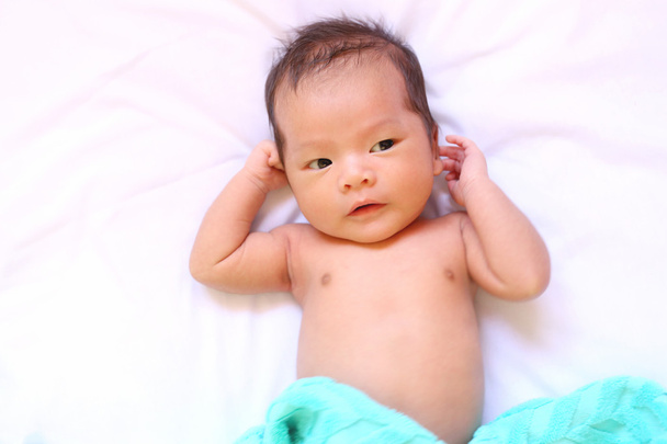 Bebé recién nacido de asia relajarse en un buen estado de ánimo en la cama blanca
. - Foto, Imagen