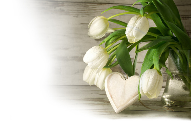 white tulips and a wooden heart shape against gray wood, corner  - Fotografie, Obrázek