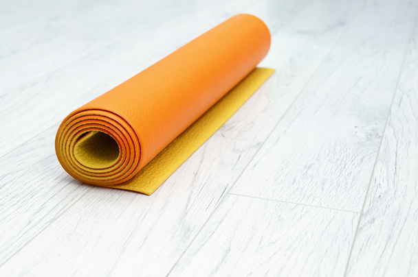 helder oranje yoga mat op een licht grijs laminaat, binnenshuis - Foto, afbeelding