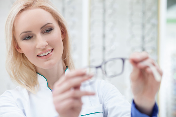 Pretty female ophthalmologist is showing new glasses - 写真・画像
