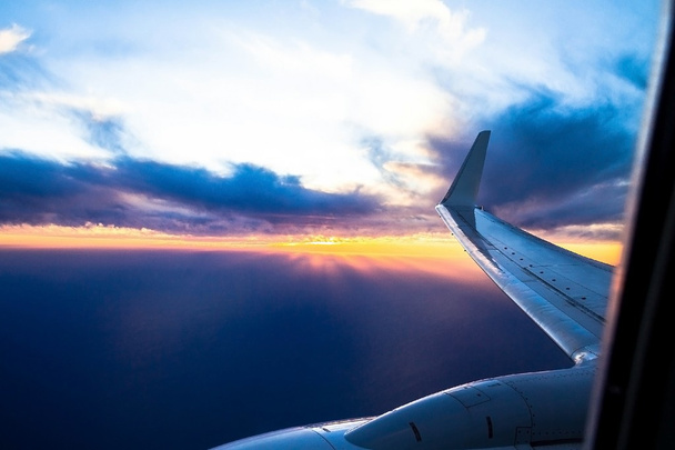 De vliegtuigen van de vleugels bij zonsondergang. Uitkijkend door vliegtuig raam - Foto, afbeelding
