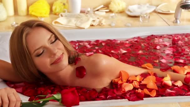 Dziewczyna przy kąpieli z płatkami róż w wanną. - Materiał filmowy, wideo