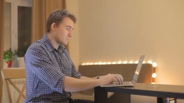 Jonge man aan het werk op een laptop thuis - Video