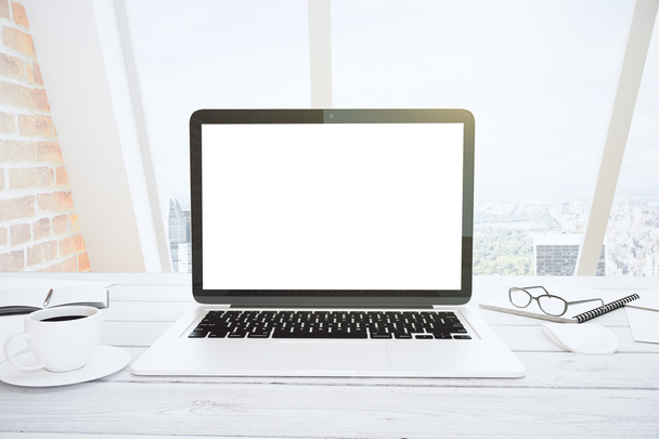Blank white laptop screen on white wooden table with eyeglasses  - Foto, Bild