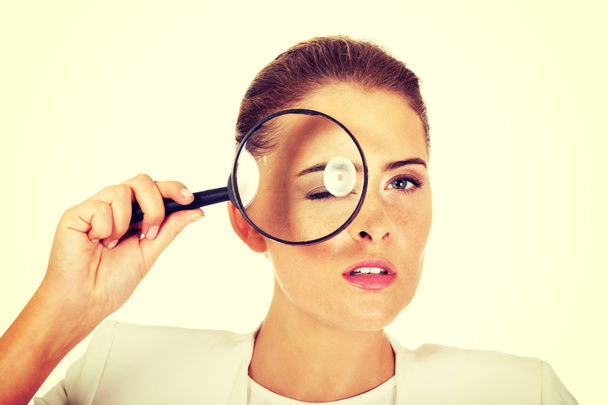 Businesswoman looking into a magnifier and have a big eye - Foto, imagen