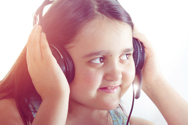 Beautiful girl holds two hands headphones and enjoy music, toned photo - Photo, Image