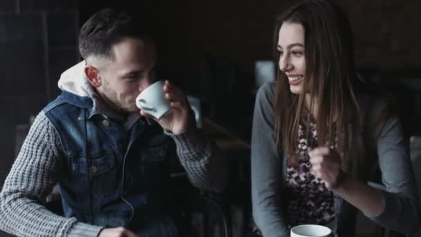Handsome male and female in their 20s sitting at the cafe, drinking tea and coffee, have a nice talk and smiling. - Footage, Video