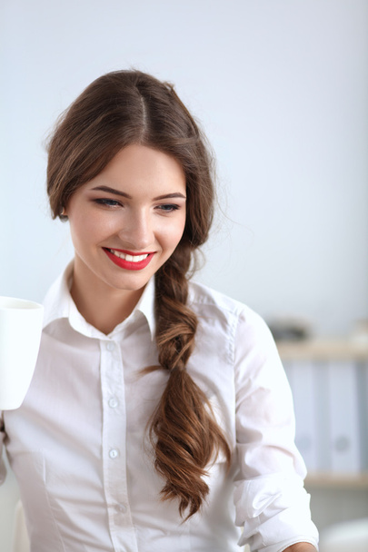Attractive businesswoman sitting  on desk in the office - Photo, image