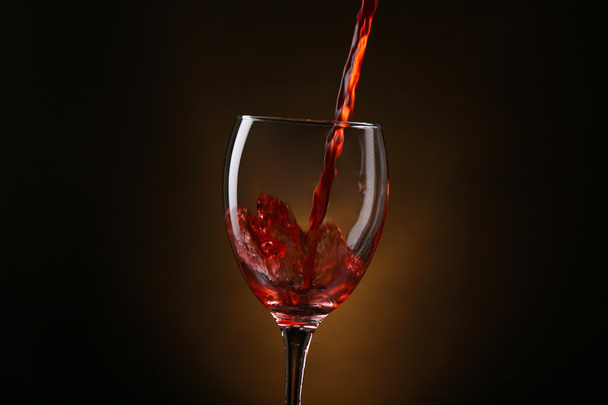 Wine pouring in glass on brown background - Fotografie, Obrázek