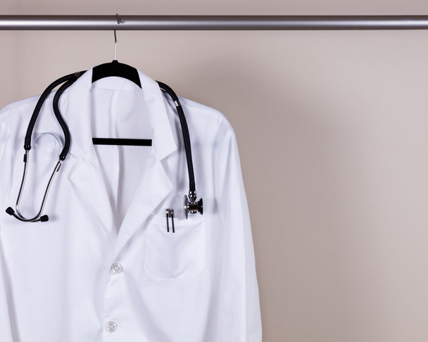 Manteau de consultation médicale blanc avec stéthoscope et stylos sur han
 - Photo, image