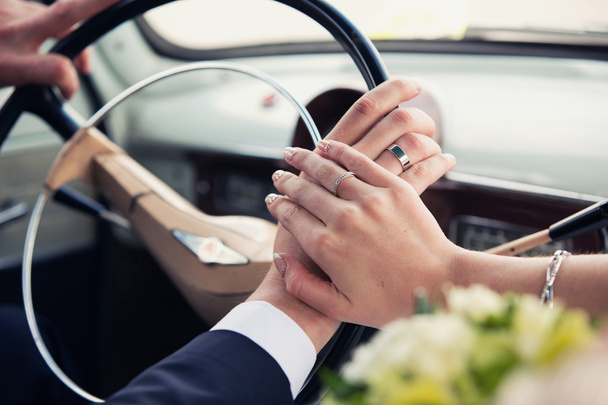 manos de los recién casados en una rueda de coche retro
 - Foto, Imagen