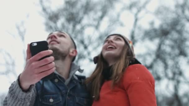 romantischer Moment eines süßen Paares, das ein Selfie macht, während Vögel über den Himmel fliegen. Mann und Frau in ihren Zwanzigern fotografieren im Winter auf mobilen Geräten im Freien. - Filmmaterial, Video