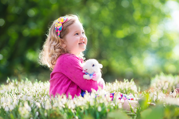 Little girl playing with bunny on Easter egg hunt - Photo, Image