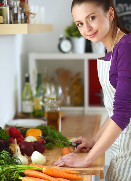 Young woman cutting vegetables in the kitchen - Foto, immagini