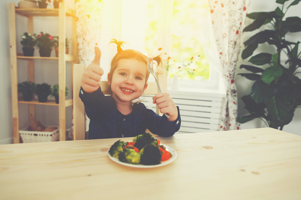 happy child girl loves to eat vegetables and showing thumbs up - Фото, зображення