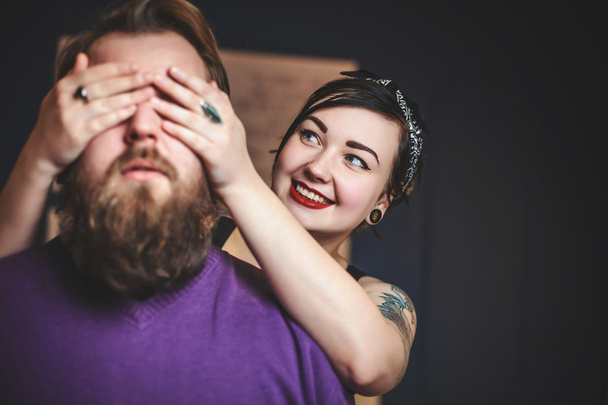 young couple in love with tattoos having fun, the girl closes hands eyes guy - Photo, Image