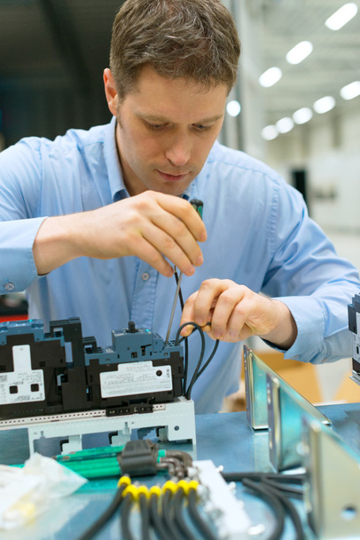 Handsome worker assembling electronic components at the factory. - Photo, Image