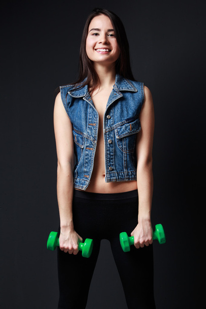  vrouw in een denim vest en zwarte broek uitvoeren workout met  - Foto, afbeelding