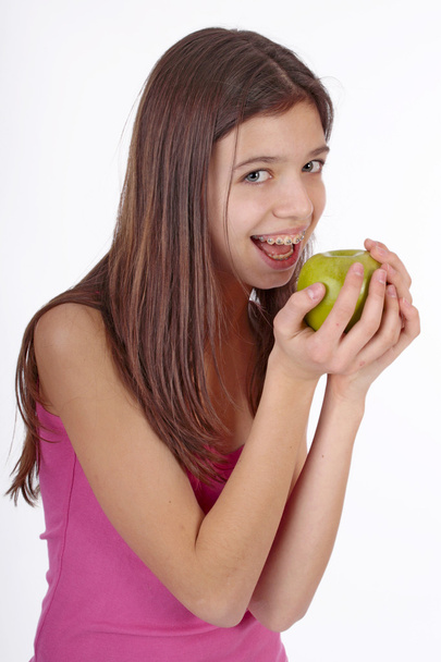 きれいな女の子を口を開けて食べる緑熟したリンゴ 1 個 - 写真・画像