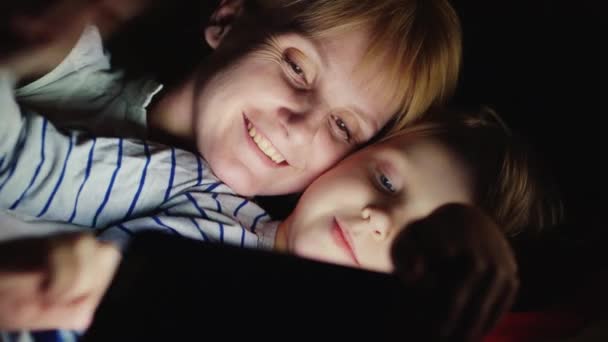 Mother and daughter enjoy the tablet lie in bed at night - Imágenes, Vídeo