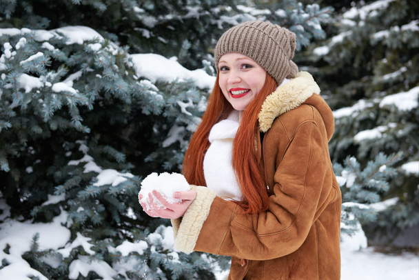 Femme prendre une poignée de neige dans le parc d'hiver le jour. Sapins avec neige
.  - Photo, image