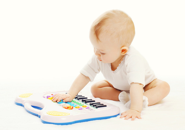 Little baby playing with toy piano on a white background - Φωτογραφία, εικόνα