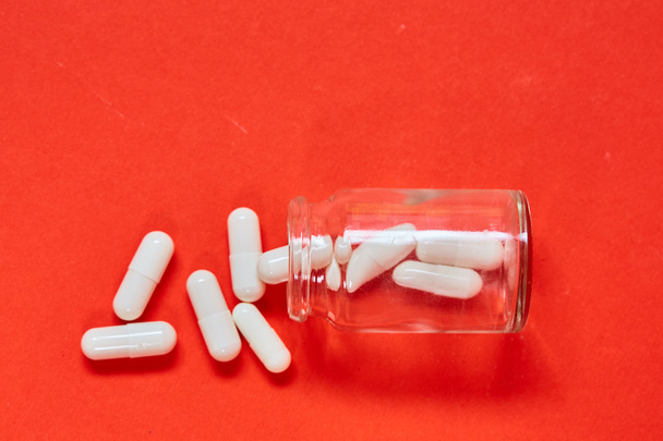 Pilules renversant hors de la bouteille de pilule sur le rouge. Vue supérieure avec espace de copie
. - Photo, image