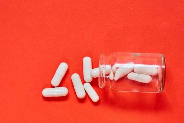 Pilules renversant hors de la bouteille de pilule sur le rouge. Vue supérieure avec espace de copie
. - Photo, image