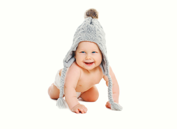 Happy cute smiling baby in knitted grey hat crawls on white back - Photo, Image