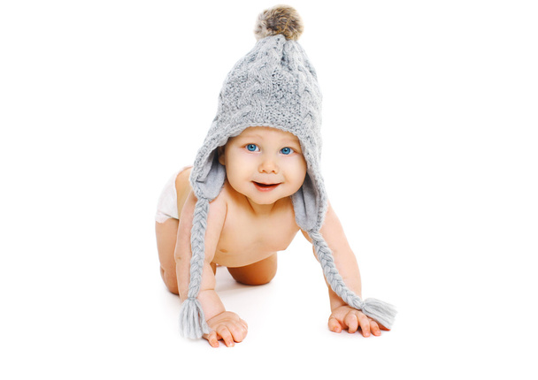 Χαριτωμένο μωρό πορτραίτο σε γκρι πλεκτό καπέλο σέρνεται σε λευκό αμουδερές - Φωτογραφία, εικόνα