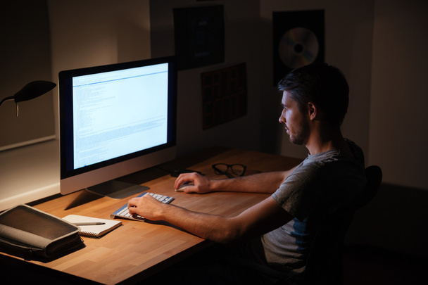 Man sitting in dark room and using computer - Photo, image