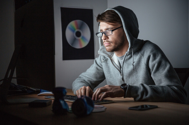 Задуманный человек в очках и толстовке, работающий за компьютером
  - Фото, изображение