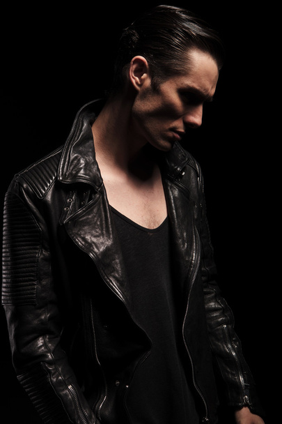 confident rocker in leather posing in studio looking down  - Zdjęcie, obraz