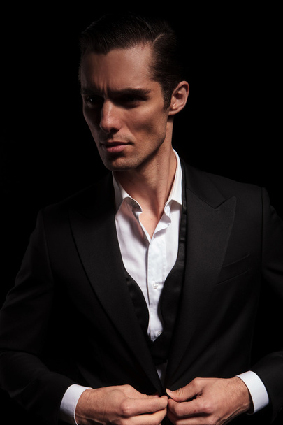 businessman in black suit in dark studio closing his jacket - Zdjęcie, obraz