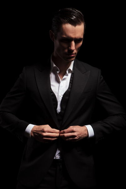 elegant man in black tuxedo posing in dark studio - Φωτογραφία, εικόνα