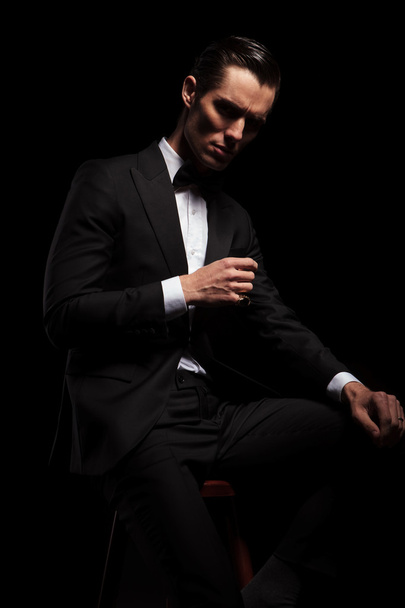 retrato lateral de hombre de negocios en negro posando sentado en la oscuridad
  - Foto, imagen