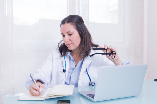 Retrato de médico feminino ocupado à mesa
 - Foto, Imagem