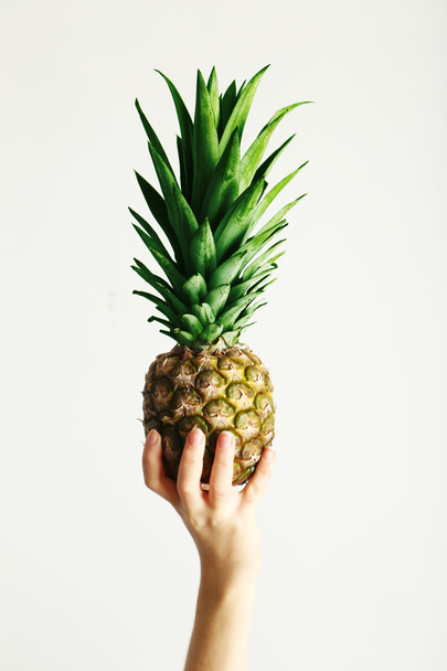 Female hand holding ripe pineapple - Fotoğraf, Görsel