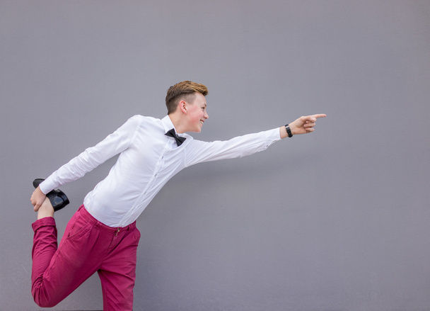 Young handsome man against gray wall pointing direction - 写真・画像