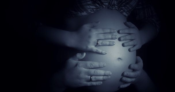 Manos y vientre: vientre de mujer embarazada cogido de la mano de madre, padre e hijo - Foto, imagen