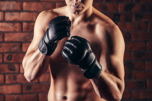 portrait of mma fighter in boxing pose against brick wall - Fotó, kép