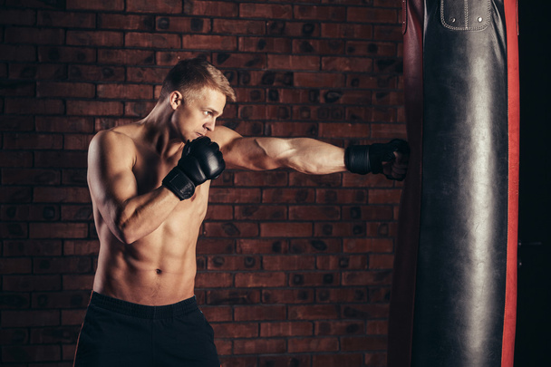 Boxer training on a punching bag in the gym. - Fotó, kép
