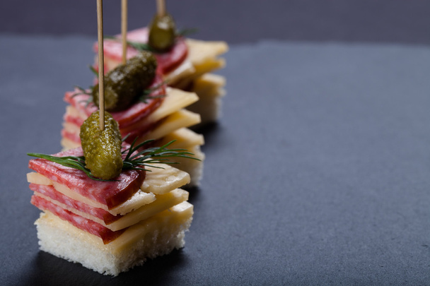 Small snacks canape with salami, cheese and pickle on skewer on  - Фото, изображение