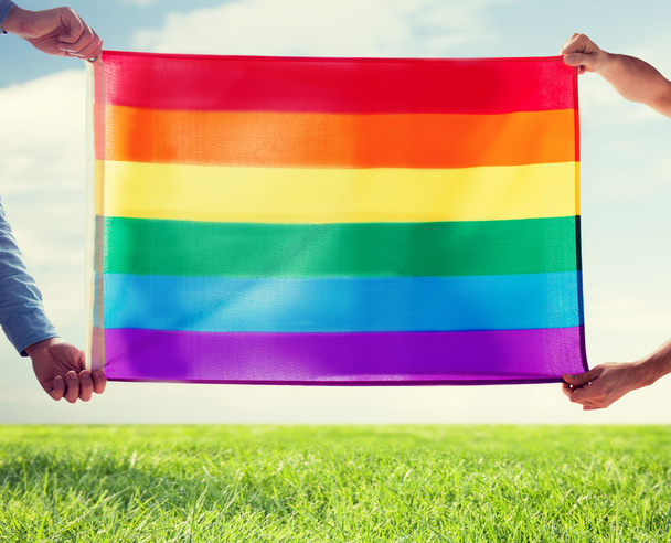 close up of male gay couple holding rainbow flag - Foto, afbeelding