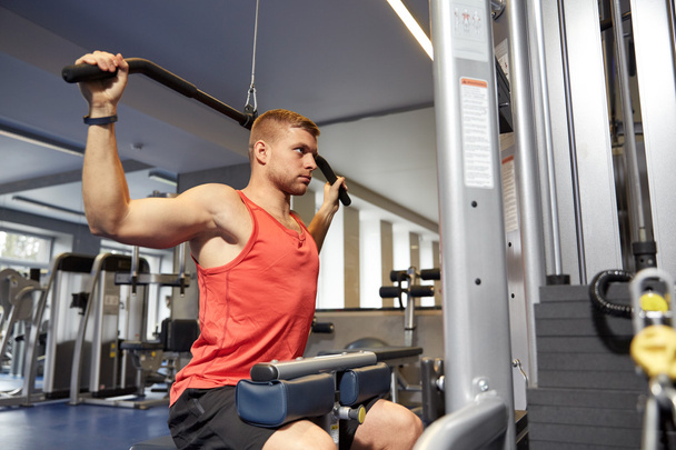 man flexing muscles on cable machine gym - Fotó, kép