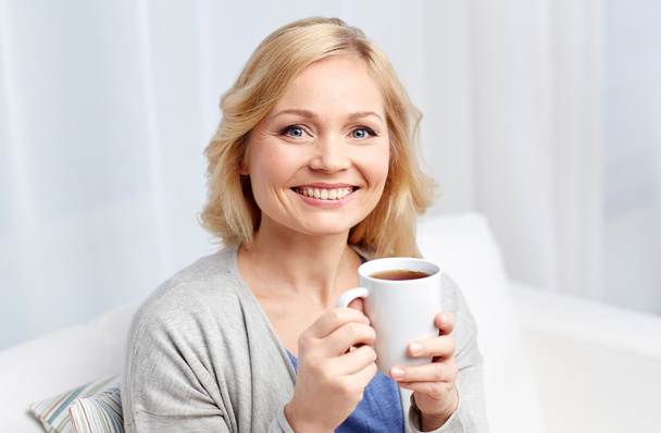 smiling woman with cup of tea or coffee at home - Φωτογραφία, εικόνα