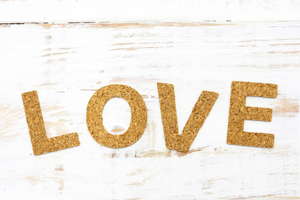 η λέξη αγάπη φελλό σε άσπρο φόντο ξύλου - Φωτογραφία, εικόνα