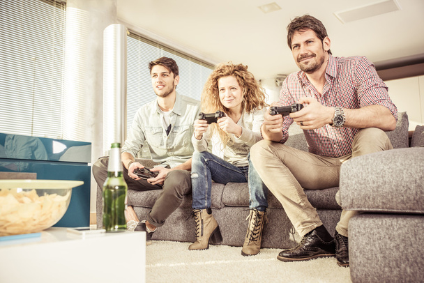 Друзья играют в видеоигры в гостиной
 - Фото, изображение