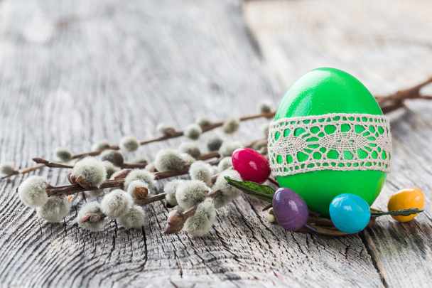Green Easter egg decorated with lace and willow branch on wooden background. Selective focus - Photo, Image